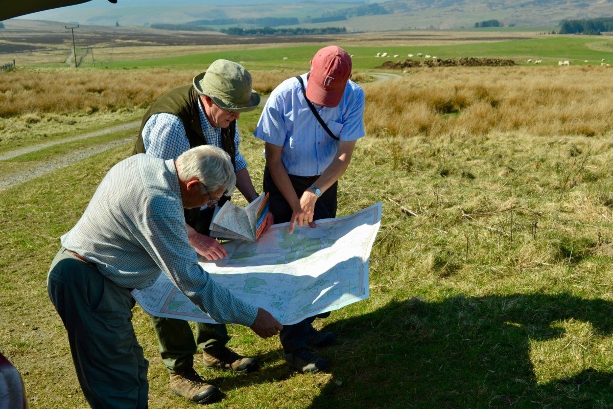 Three people in the scottish landscape, looking at a map